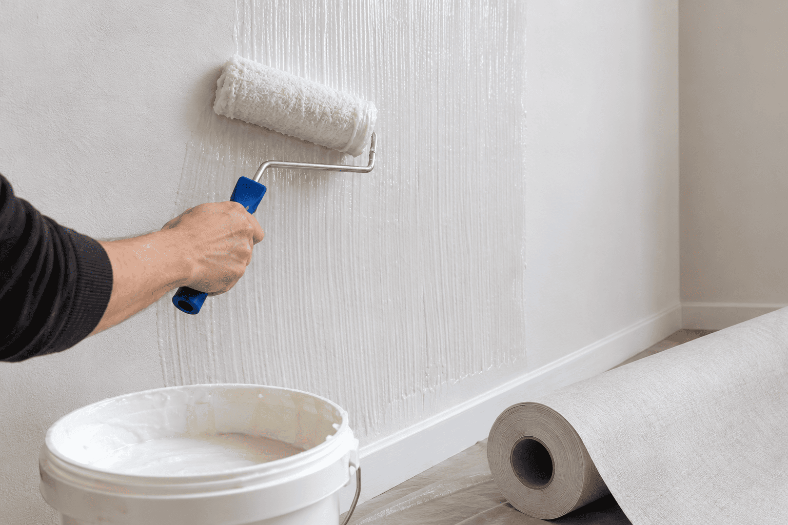 Applicazione della colla a parete per la posa della carta da parati in tessuto non tessuto